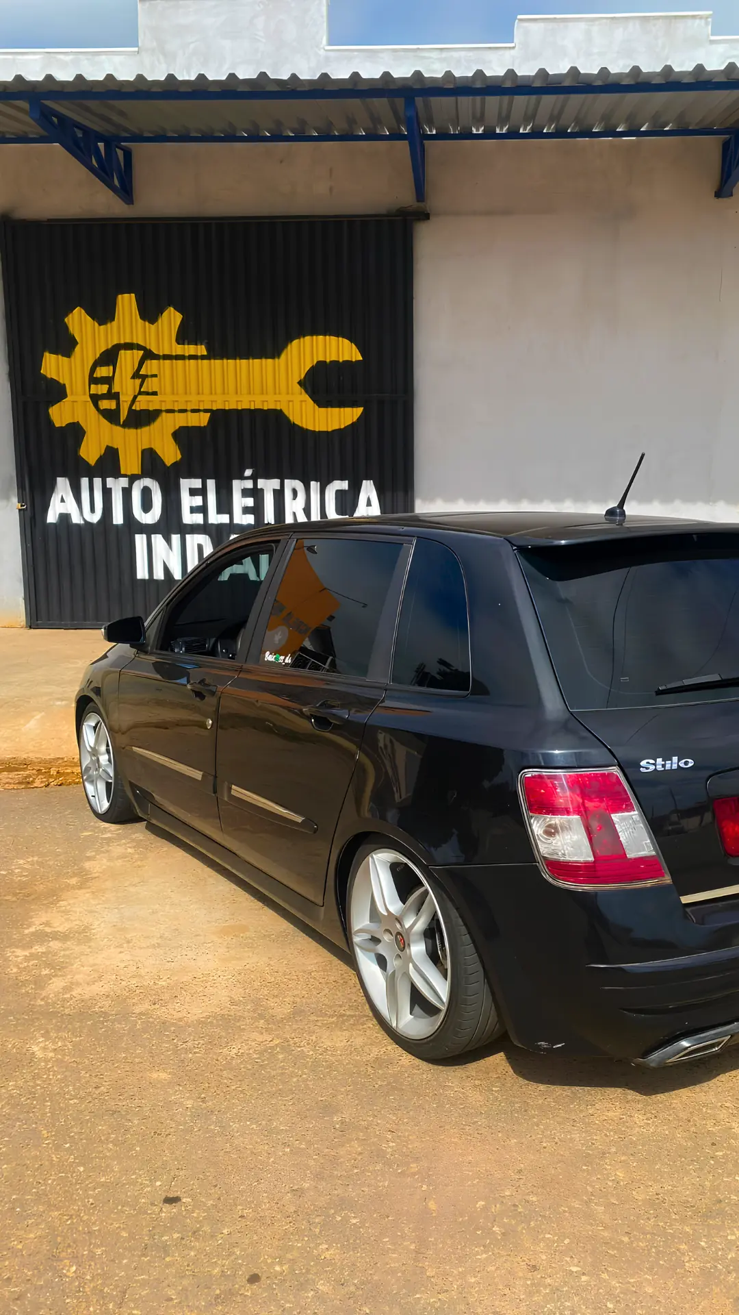 Fachada da Auto Elétrica Indaiá com a placa pintada e um carro estacionado em frente